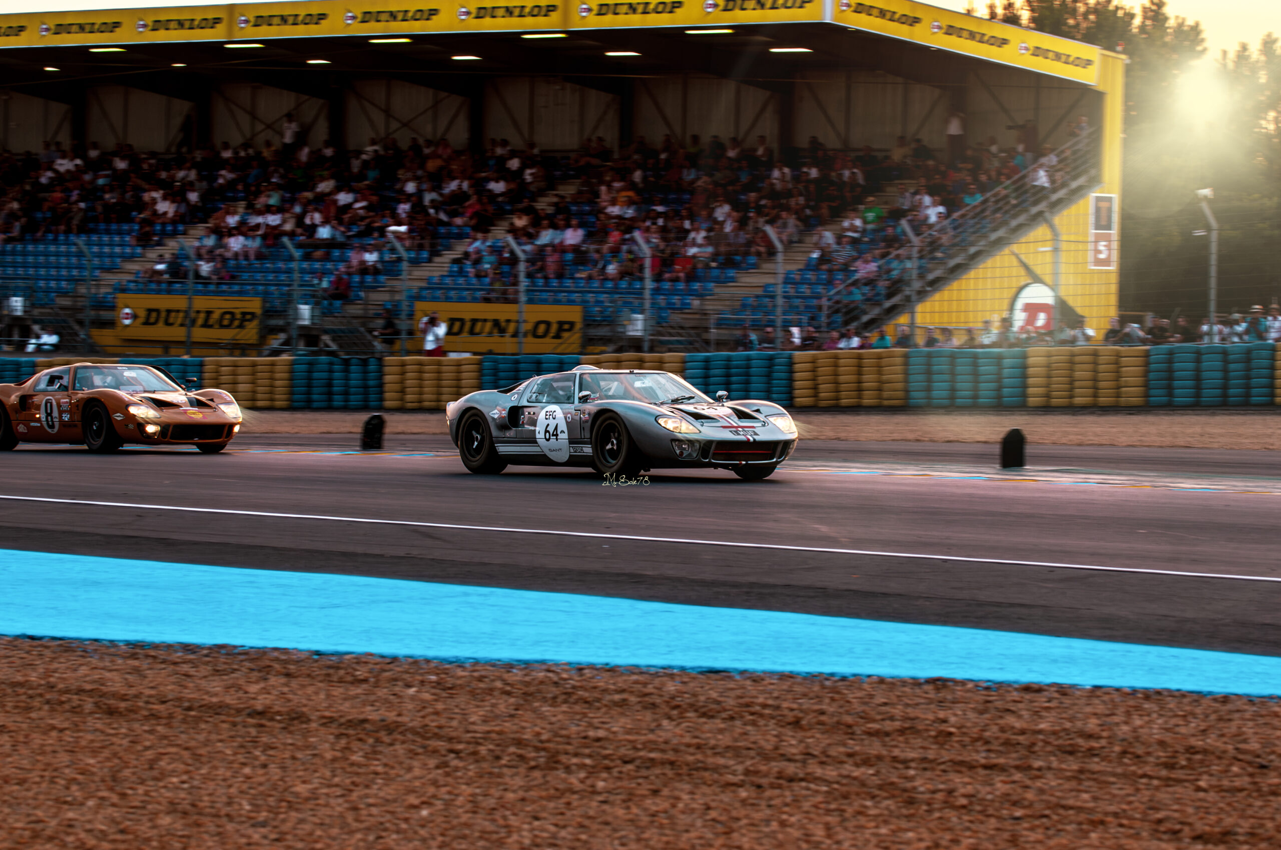 Ford GT40 Mk I numero 64 in azione sul circuito di Le Mans Classic davanti alla tribuna Dunlop durante una sessione di gara.