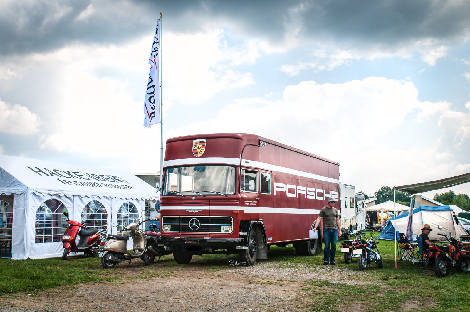 Camion Porsche d'epoca parcheggiato al campeggio della 24 Ore di Le Mans tra tende e scooter