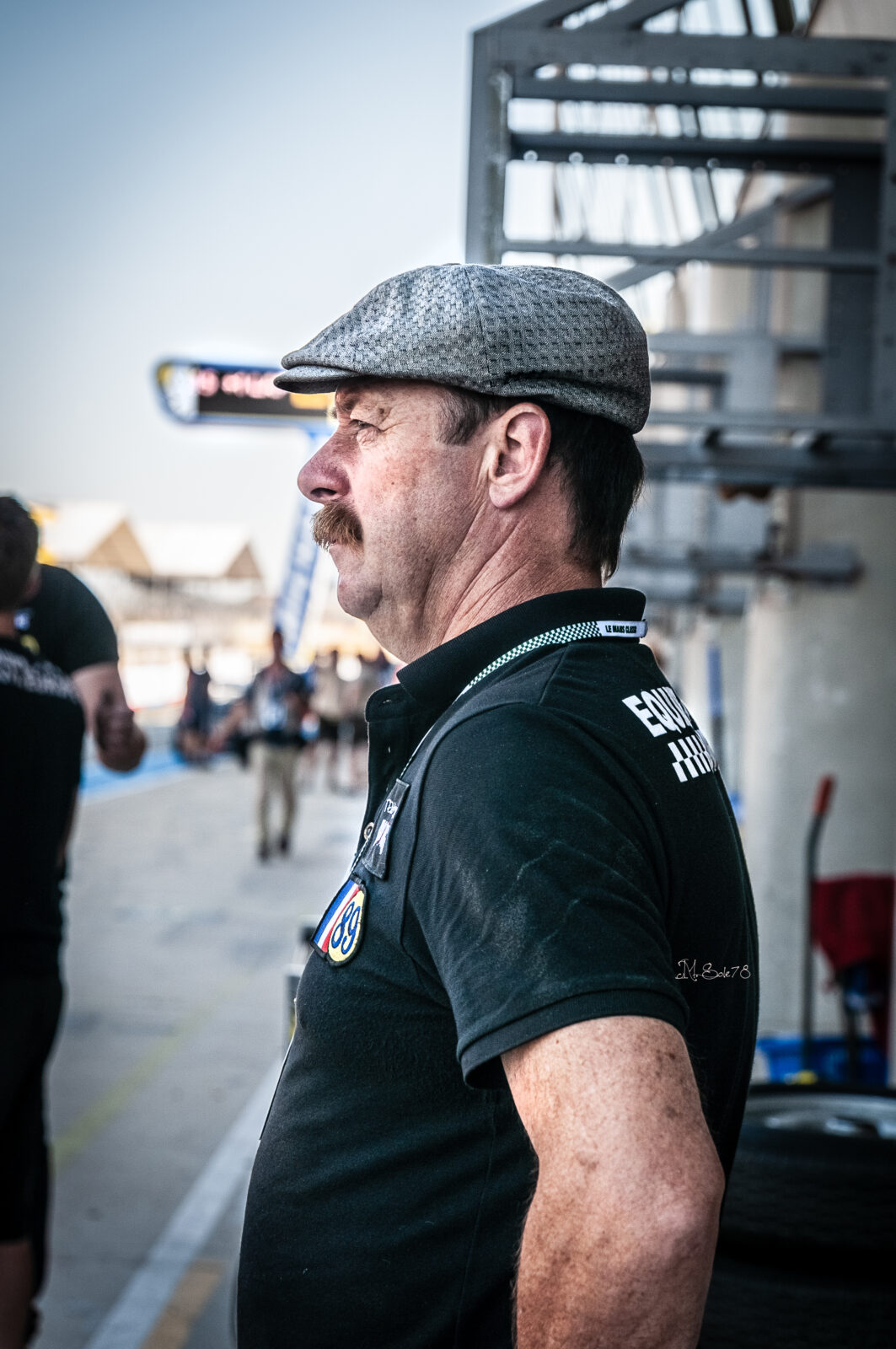 Uomo con coppola e baffi al paddock della 24 Ore di Le Mans in attesa della gara