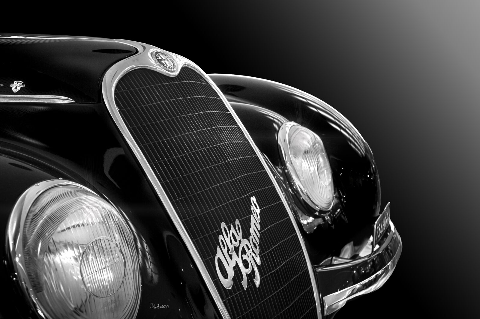 Dettaglio in bianco e nero del frontale di un'Alfa Romeo 6C carrozzata Touring, mascherina e faro